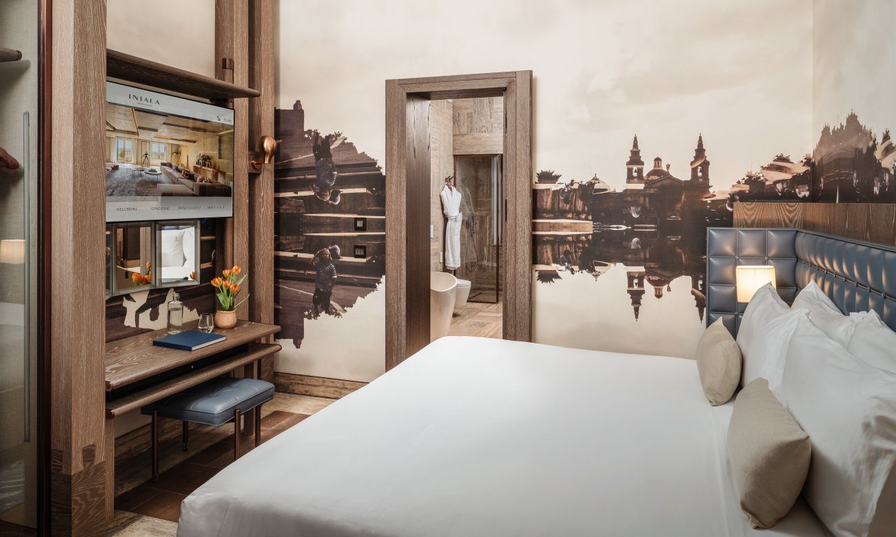 Grand Harbour View Suite bedroom with city mural and blue upholstered headboard.
