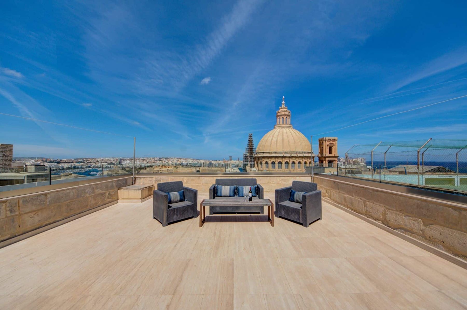 Roof terrace with chairs overlooking a church dome and Valletta skyline.