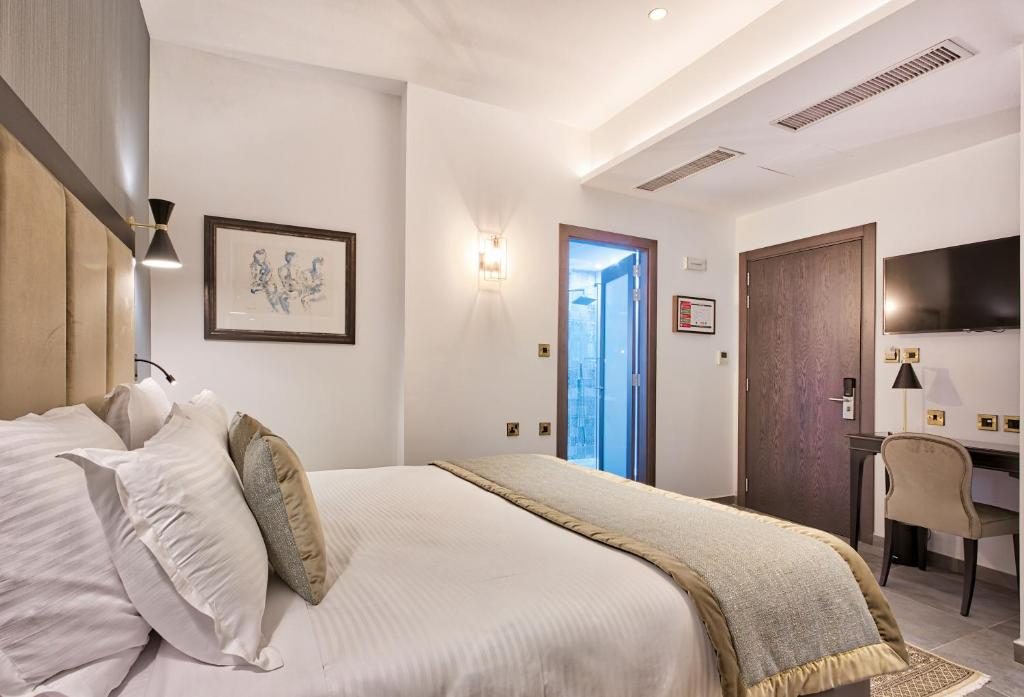 Palazzo Rosaria bedroom with padded headboard, wall lights and desk.