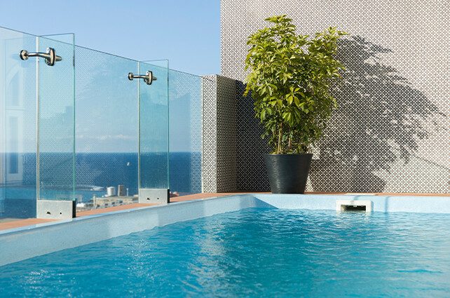 Blue rooftop plunge pool with glass screens and a potted tree at Rosselli.