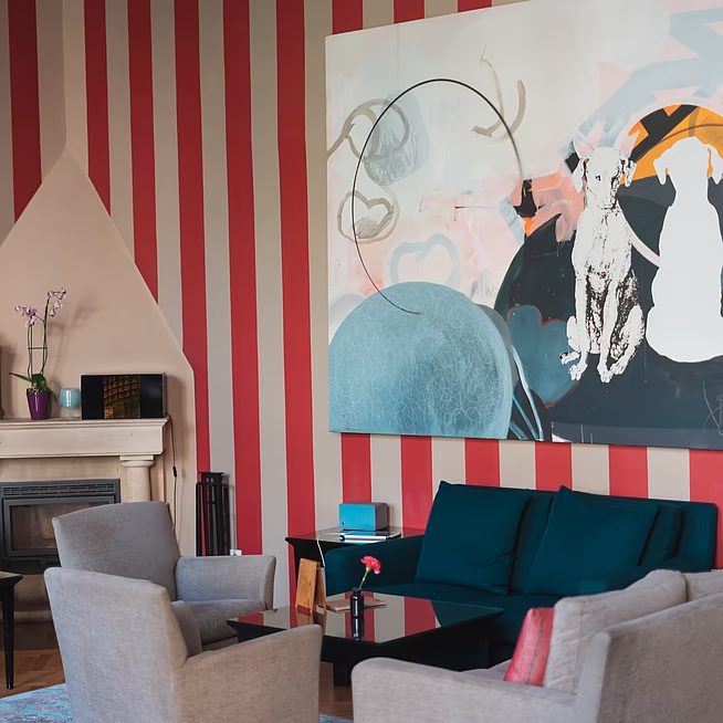 Striped salon wall, large artwork, teal sofa and grey armchairs at Altstadt Vienna.