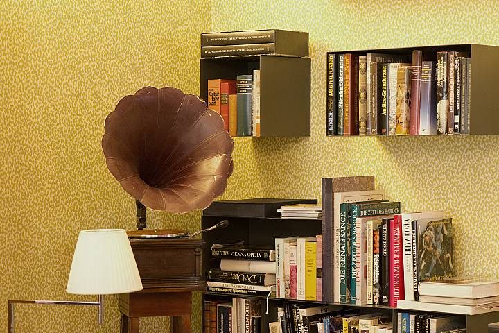 Gramophone and book shelves against a yellow patterned wall in Hotel Beethoven’s lounge.
