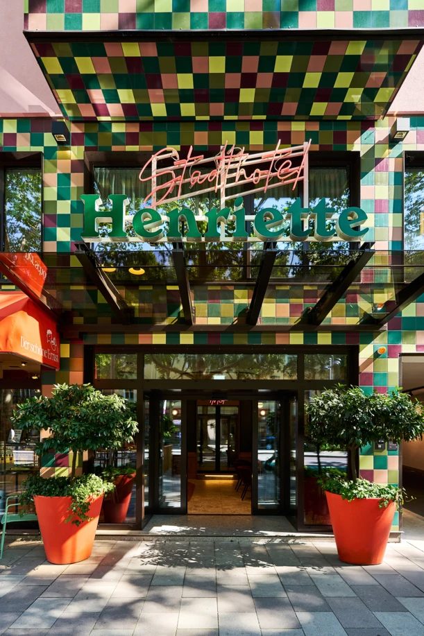 Multicoloured tiled entrance canopy with Henriette lettering and planted pots.
