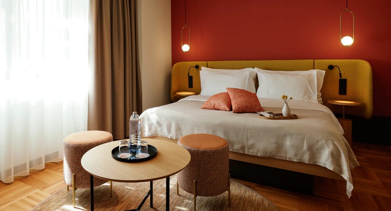 Bed with yellow headboard, red wall and round tables in a Circular Living room.