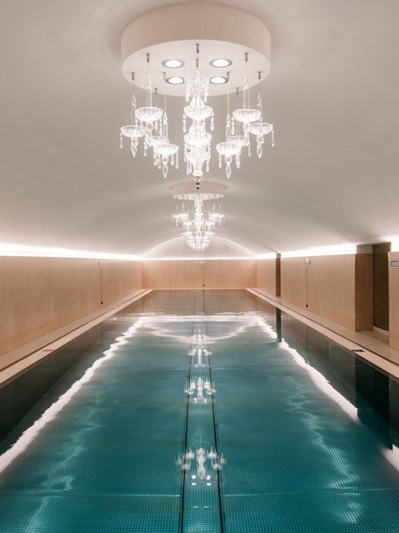 Long indoor pool beneath chandeliers at Sans Souci Wien.