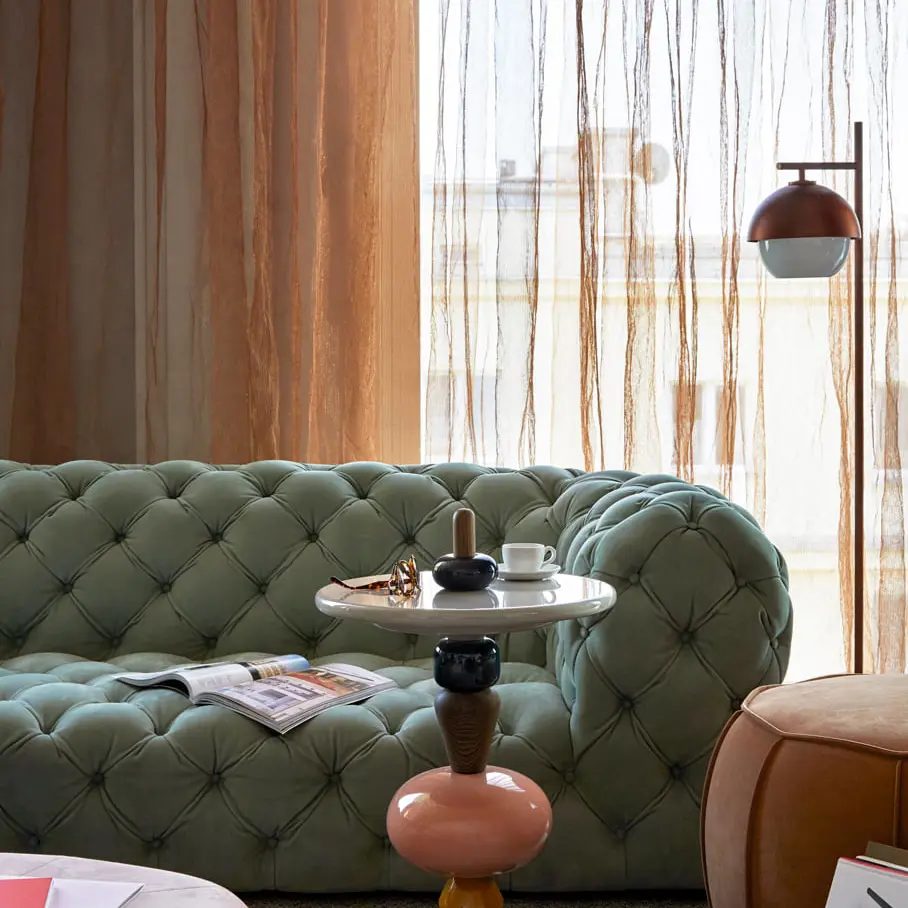 Green tufted sofa and round tables at PURO Warsaw Centrum on Widok