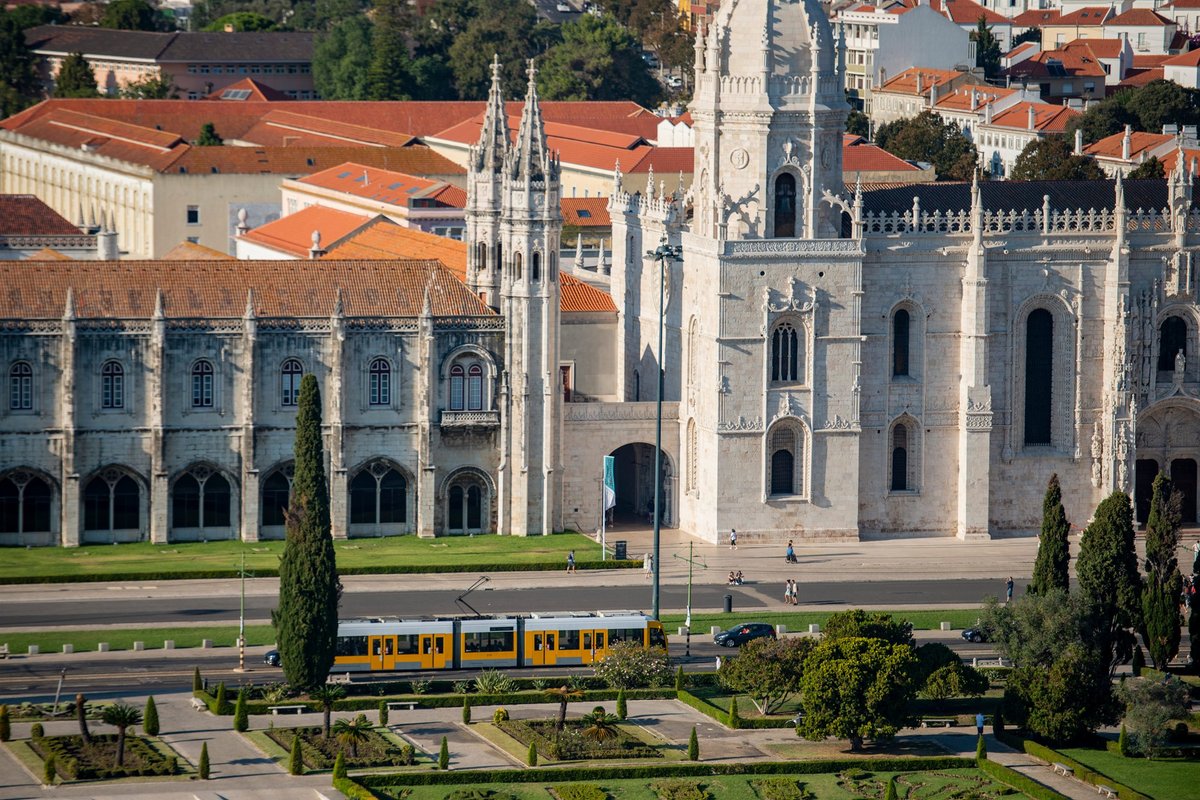 The exterior of Jerónimos Monastery in Belém with a yellow tram